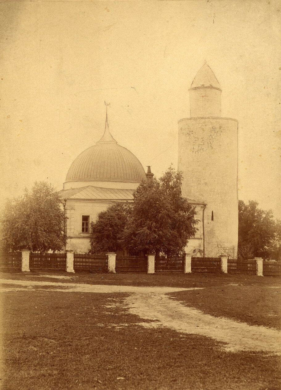 Must-valge foto valgest mošeest kõrge silindrilise kivist minaretiga puude vahel